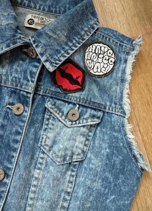 Джинсовая жилетка из денима с нашивками и бохрамой